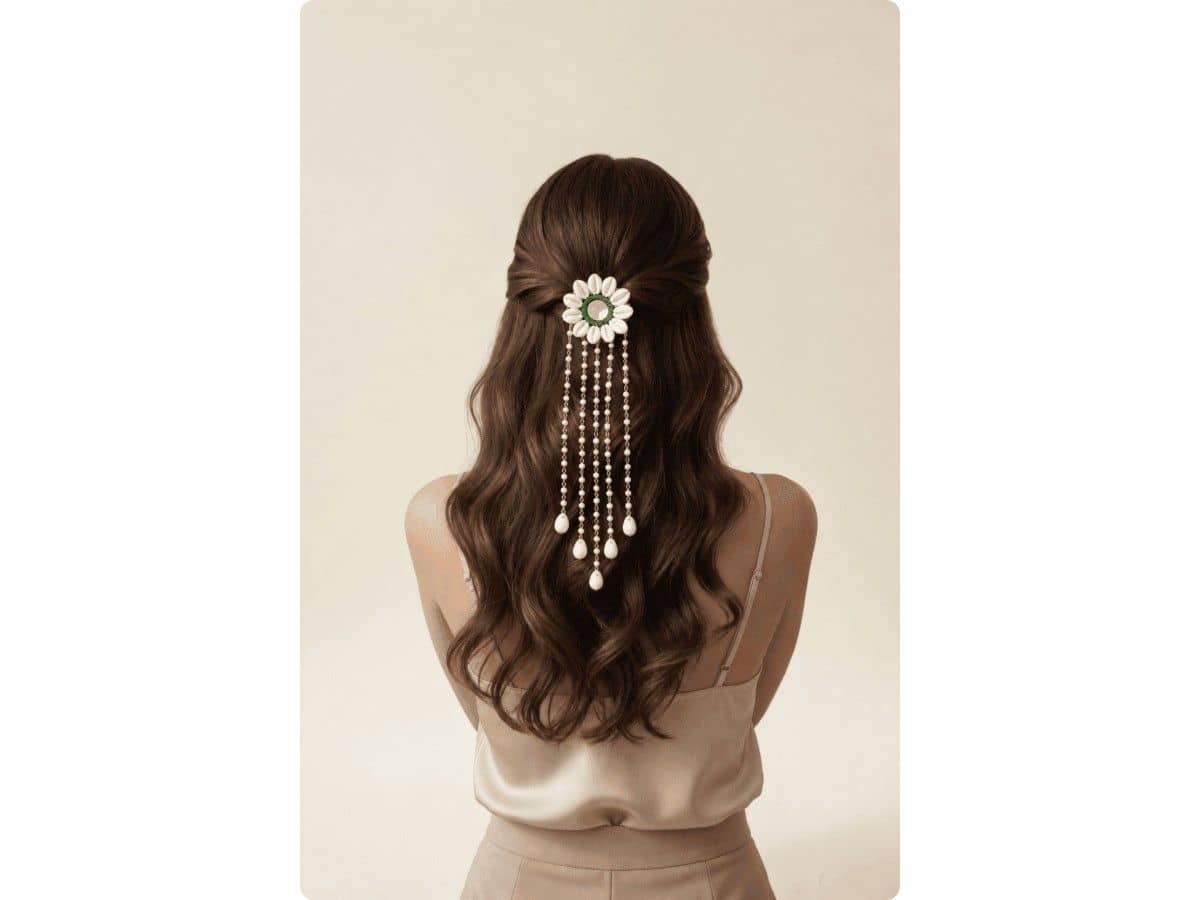 White cowrie shells around a round mirror with a green border, with long pearl chains and shell drops over half-up hair
